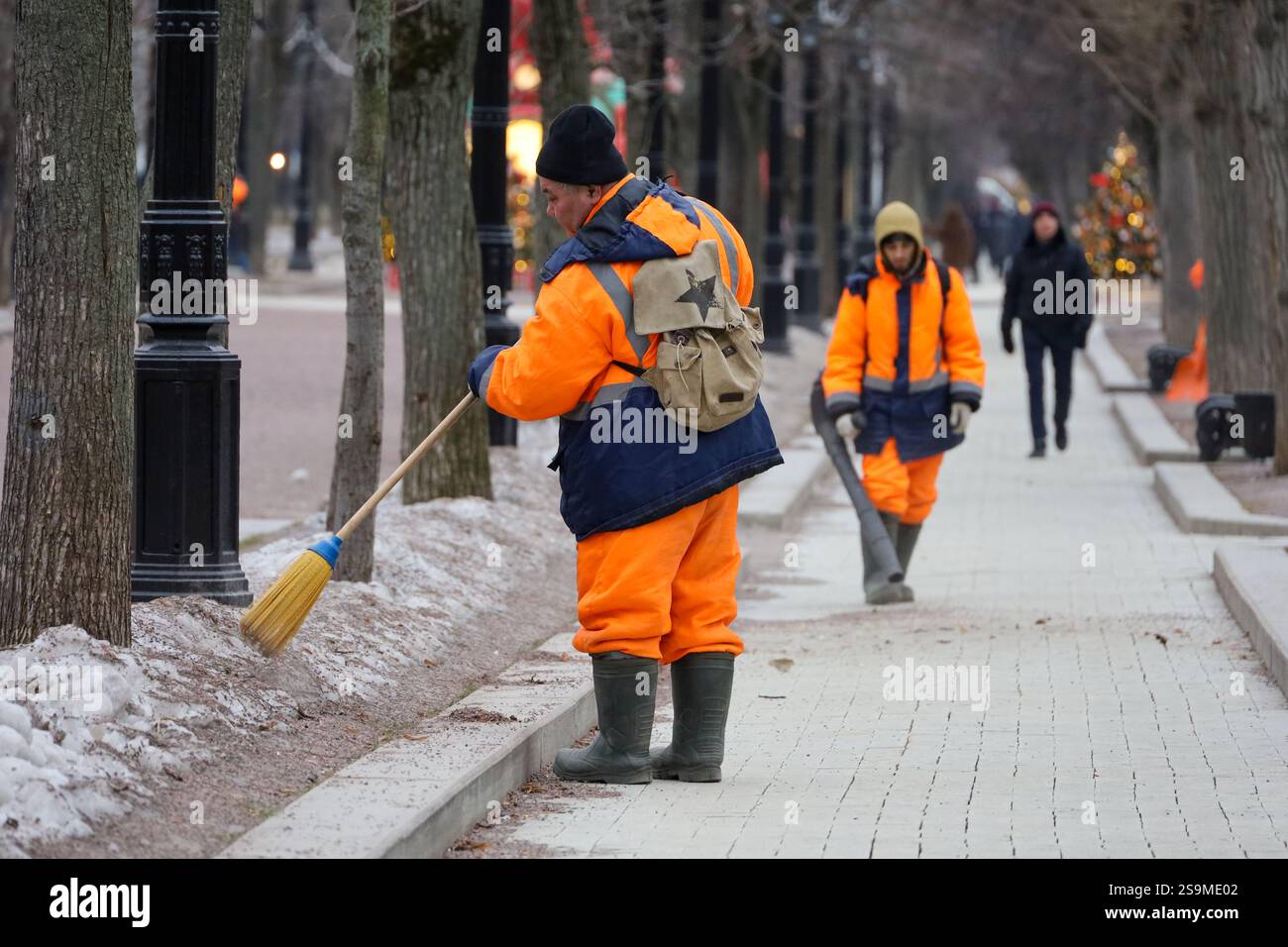 Concierges dans le parc municipal d'hiver, ouvriers municipaux masculins en uniforme. Le nettoyage des rues, concept de main-d'œuvre non qualifiée Banque D'Images