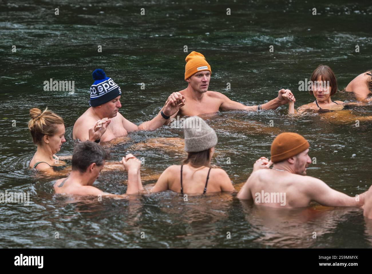Groupe de personnes en cercle glace se baignant ensemble dans l'eau froide d'une rivière dans une forêt. Méthode Wim Hof, thérapie froide, techniques respiratoires, yoga Banque D'Images