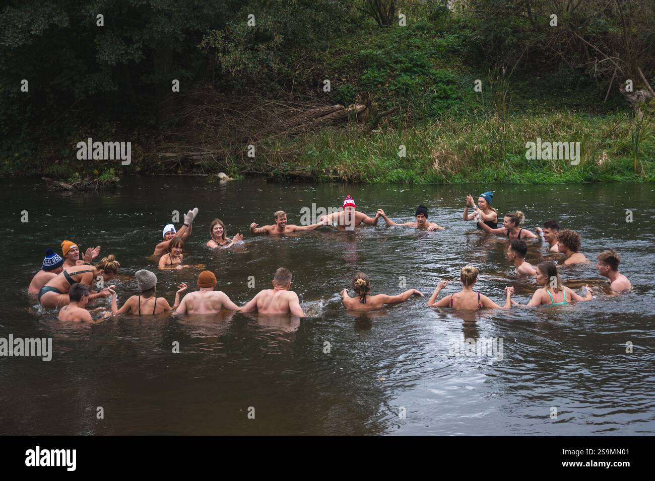 Groupe de personnes en cercle glace se baignant ensemble dans l'eau froide d'une rivière dans une forêt. Méthode Wim Hof, thérapie froide, techniques respiratoires, yoga Banque D'Images