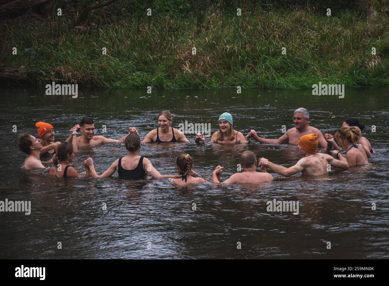 Groupe de personnes en cercle glace se baignant ensemble dans l'eau froide d'une rivière dans une forêt. Méthode Wim Hof, thérapie froide, techniques respiratoires, yoga Banque D'Images