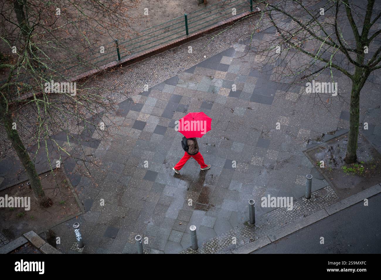 23.01.2025, Berlin, Allemagne, Europe - Une personne tenant un parapluie marche le long d'une route par une journée d'hiver humide dans la localité berlinoise de Charlottenburg. Banque D'Images