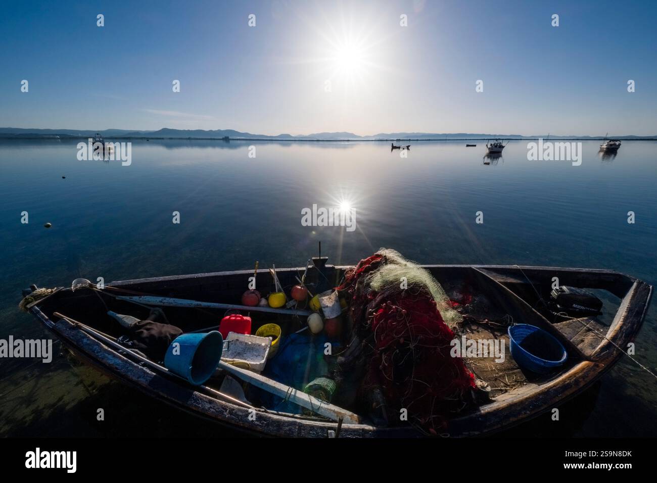Un bateau de pêche ancre dans la baie de Sant'Antioco, avec les collines et les montagnes visibles de l'autre côté. Banque D'Images