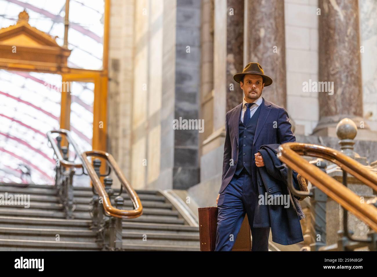 Vintage Traveler descendant escaliers avec chapeau et porte-documents Banque D'Images