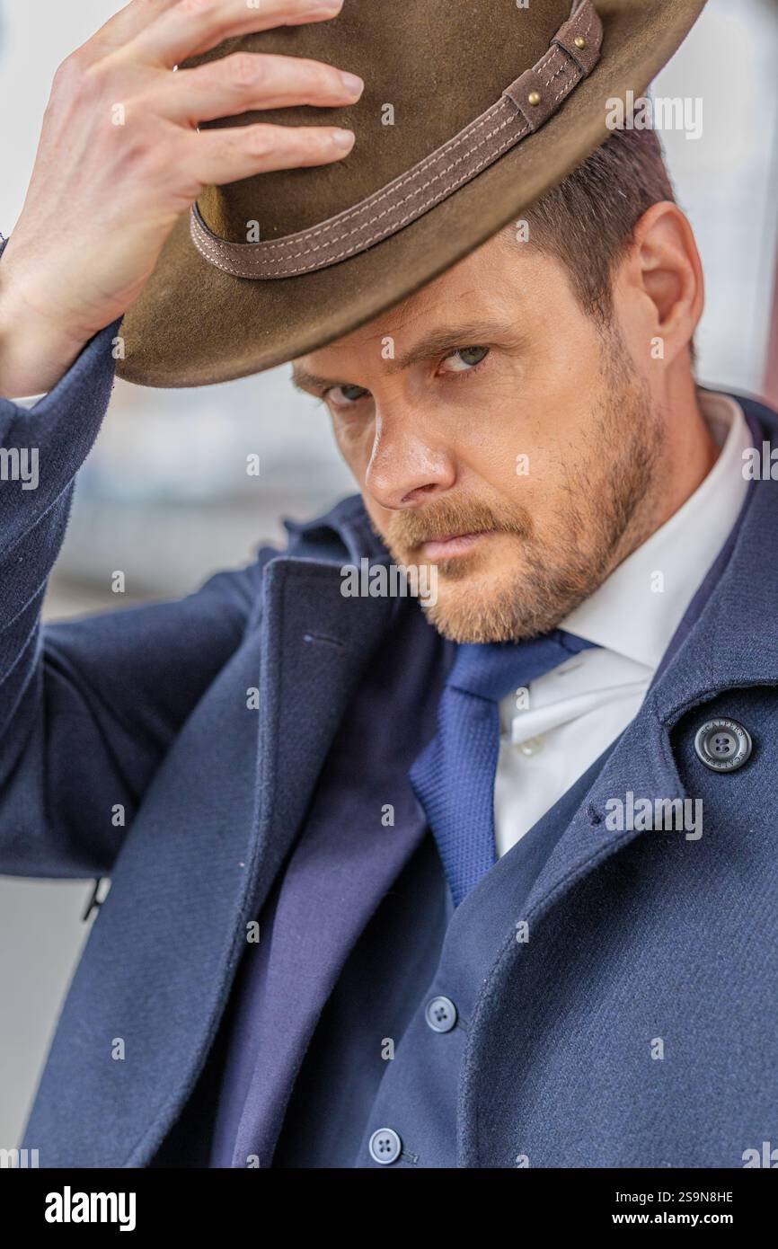 Homme penchant son chapeau avec une expression sérieuse Banque D'Images