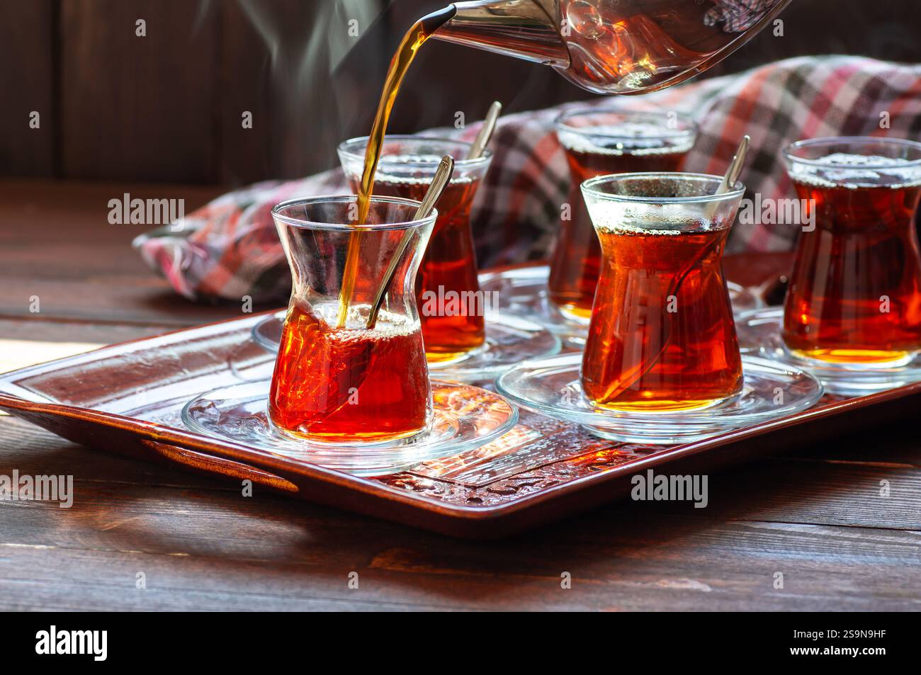 Tasse en verre de thé turc noir filtre, déversant de la théière, concept traditionnel de boisson chaude Banque D'Images