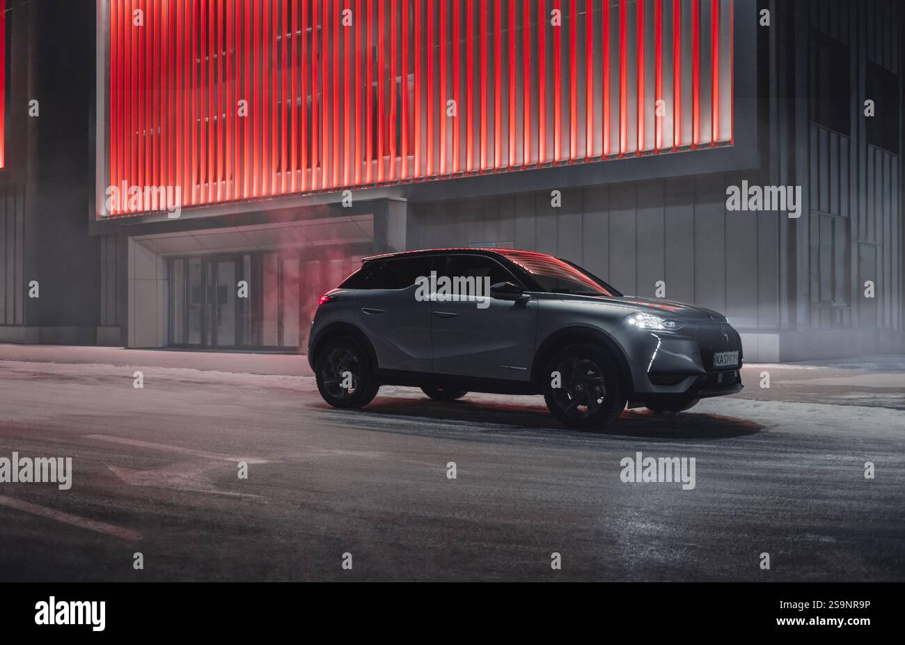 Silver DS3 Crossback sur une rue avec des lumières rouges incandescentes. Vue de trois quarts de face du VUS compact la nuit d'hiver. Banque D'Images