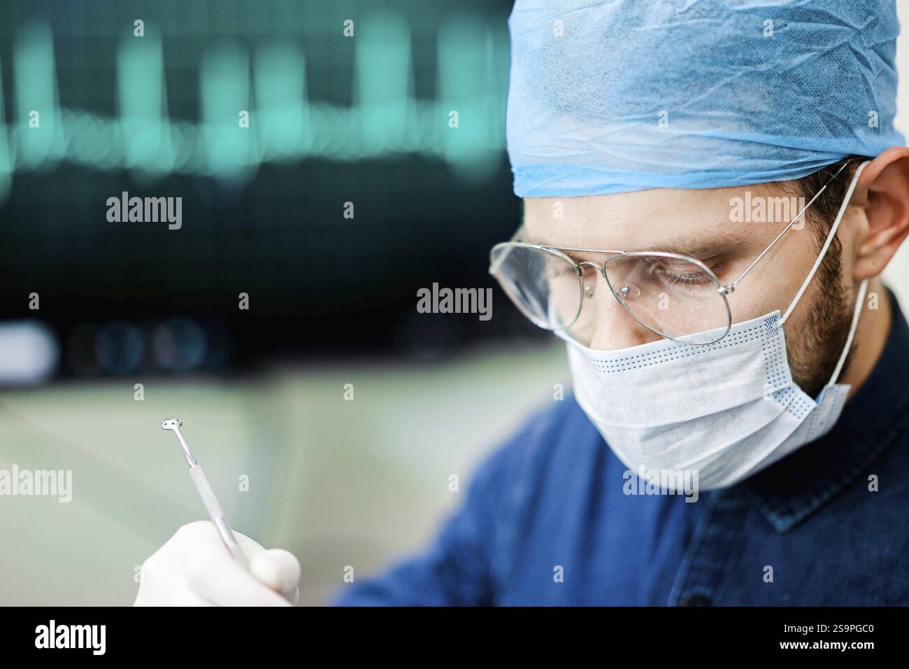 Professionnel de la santé se concentrant sur une tâche avec un affichage ECG en arrière-plan Banque D'Images