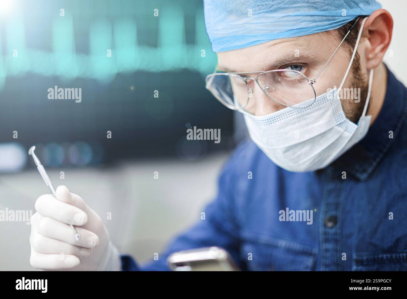 Médecin se concentrant intensément sur une tâche, avec des outils médicaux et un moniteur ECG en arrière-plan Banque D'Images