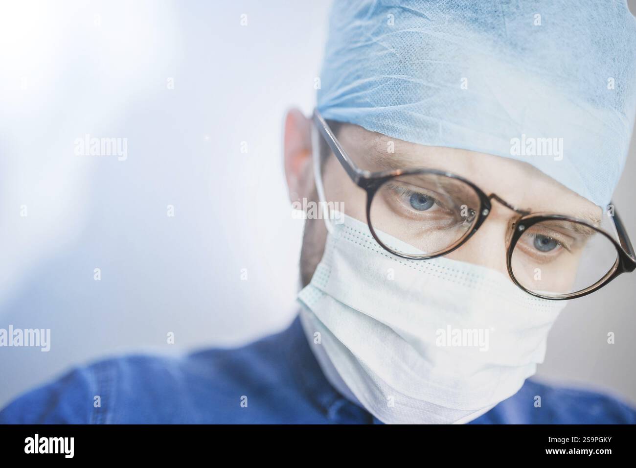 Docteur en tenue chirurgicale bleue concentré intentionnellement sur une tâche Banque D'Images
