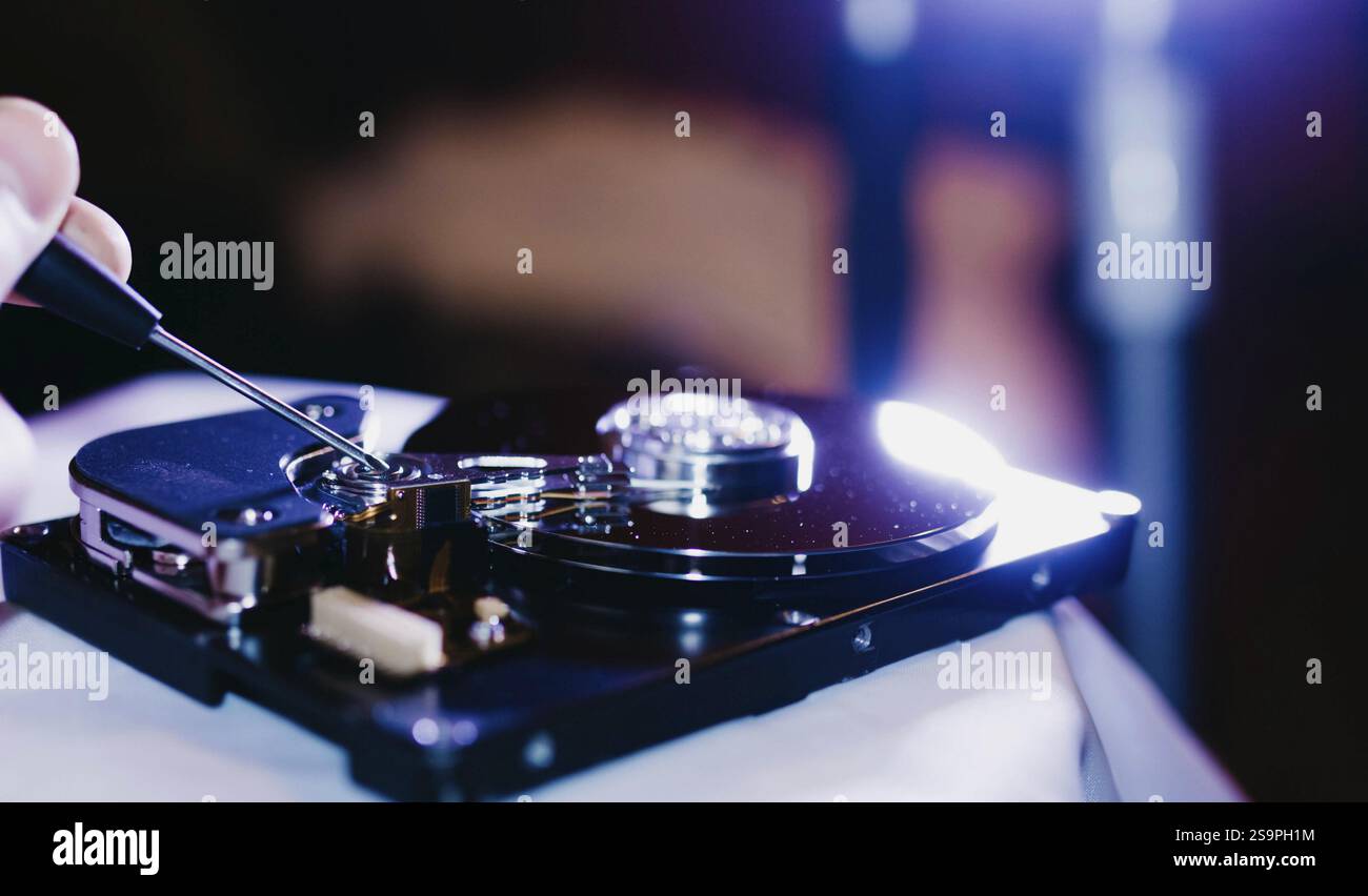 Un disque dur ouvert en cours de réparation à l'aide d'un tournevis Banque D'Images