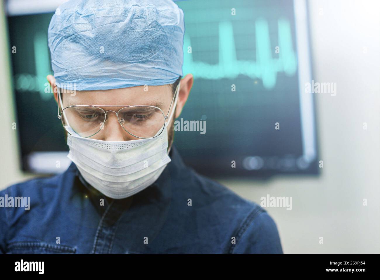 Médecin se concentrant sur une tâche médicale avec un équipement ECG affiché derrière Banque D'Images