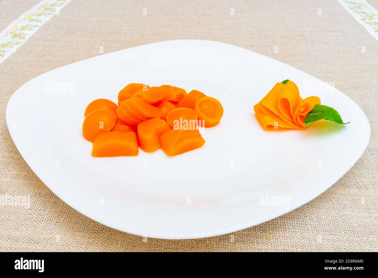 Un arrangement créatif de morceaux de carotte orange, certains en forme de rosettes, est affiché sur une plaque blanche. La présentation élégante ajoute une touche de sop Banque D'Images