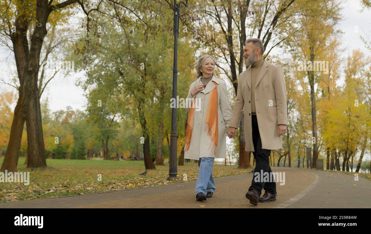 Heureux vieux couple élégant marchant dans le parc d'automne appréciant la date homme senior se promener avec la femme mature à l'extérieur dans la retraite active de la ville d'âge moyen 60 ans Banque D'Images