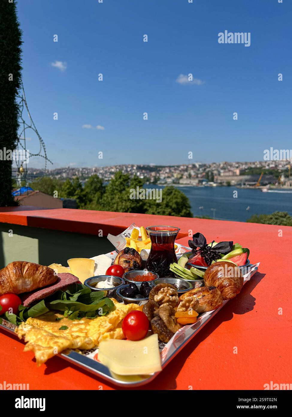 Cette image met en valeur un petit déjeuner turc coloré, avec des légumes frais, fromages, omelette, pâtisseries, fruits secs, et un verre de tradit Banque D'Images