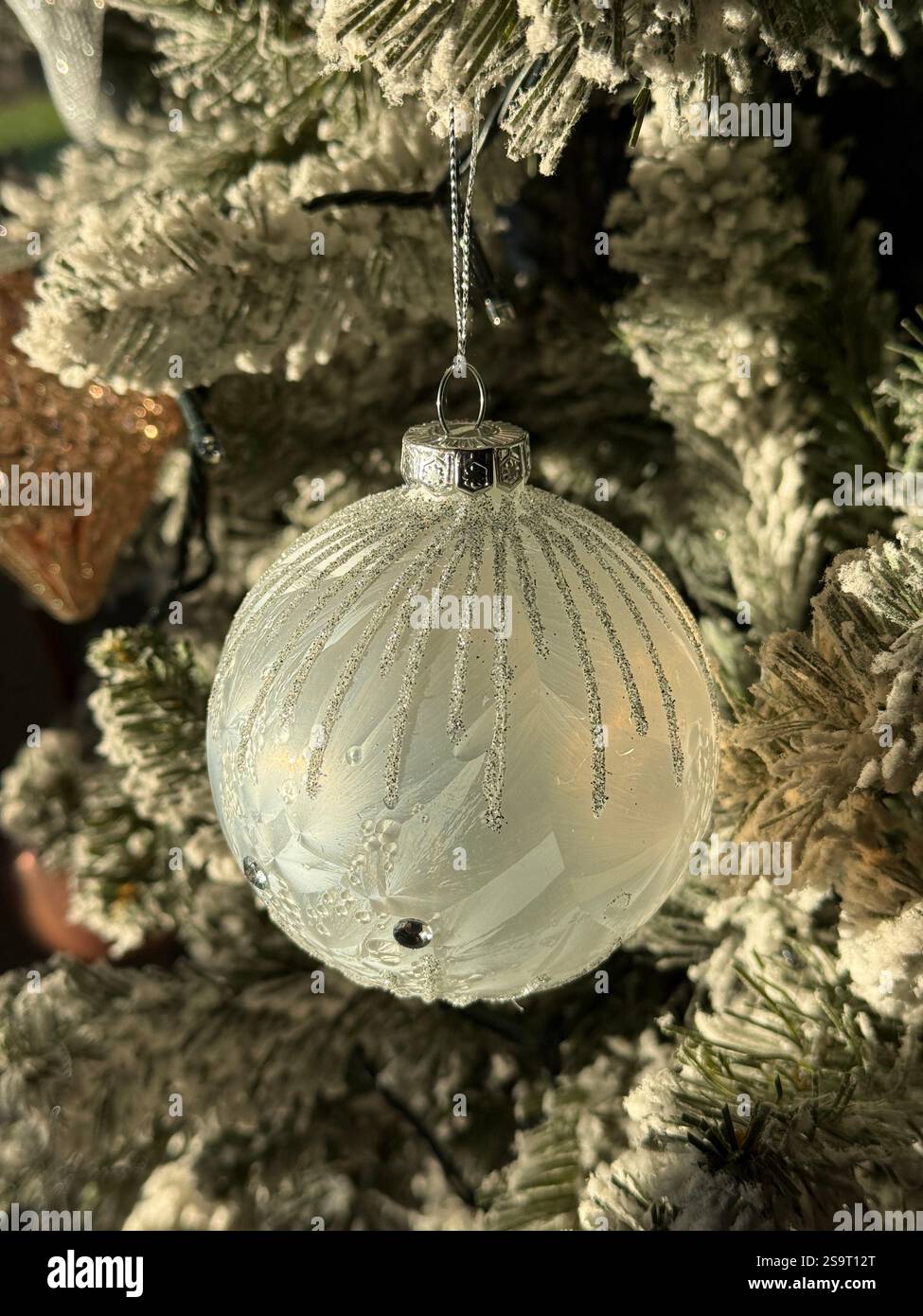 Décoration d'arbre de Noël sous la forme d'une boule nacrée blanche de style moderne avec ornementation en argent - Image de stock capturée avec un smartphone