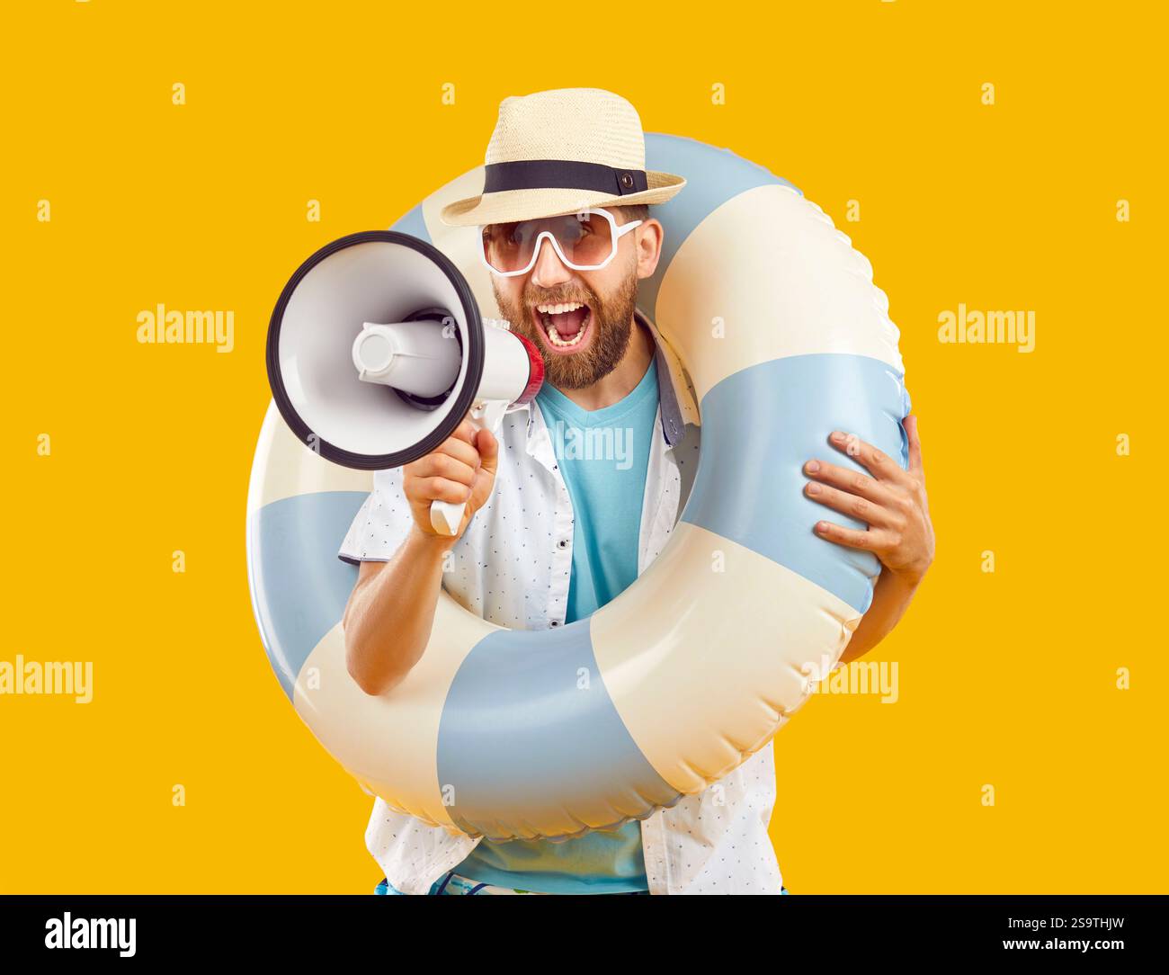 Homme joyeux crie activement dans le mégaphone annonçant des offres intéressantes pour les vacances d'été. Banque D'Images