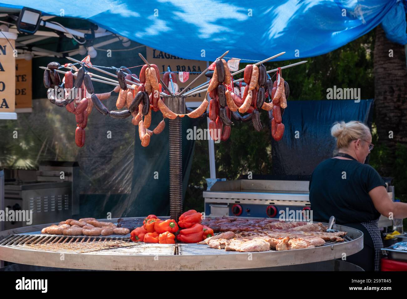 Saucisses, viande de bœuf et de porc et poivrons rouges frais grillés sur barbecue en préparation pour un festival de nourriture locale à Benalmadena, Espagne Banque D'Images