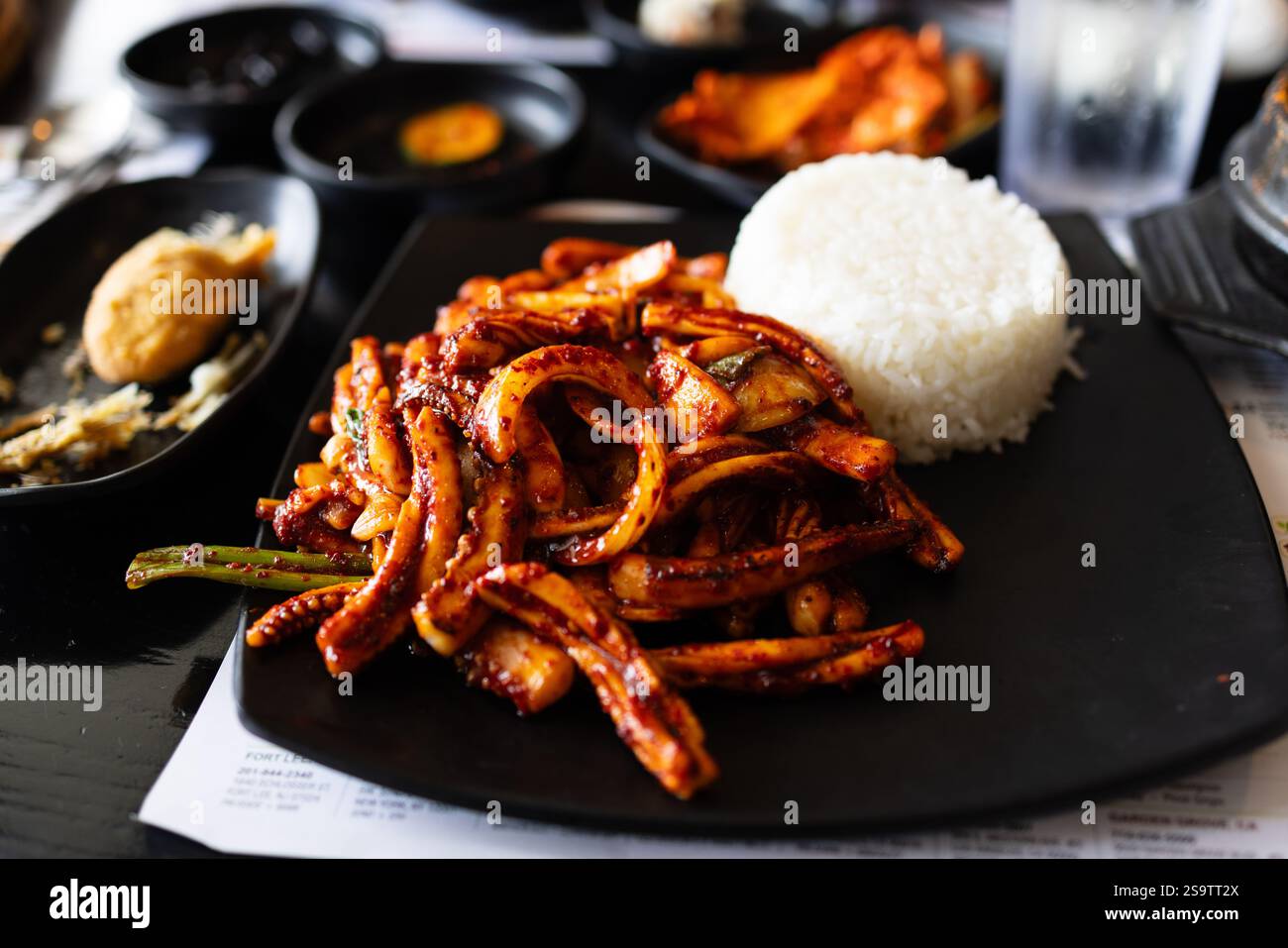 Assiette de nourriture avec du riz et de la viande dessus. L'assiette est noire et le riz blanc Banque D'Images
