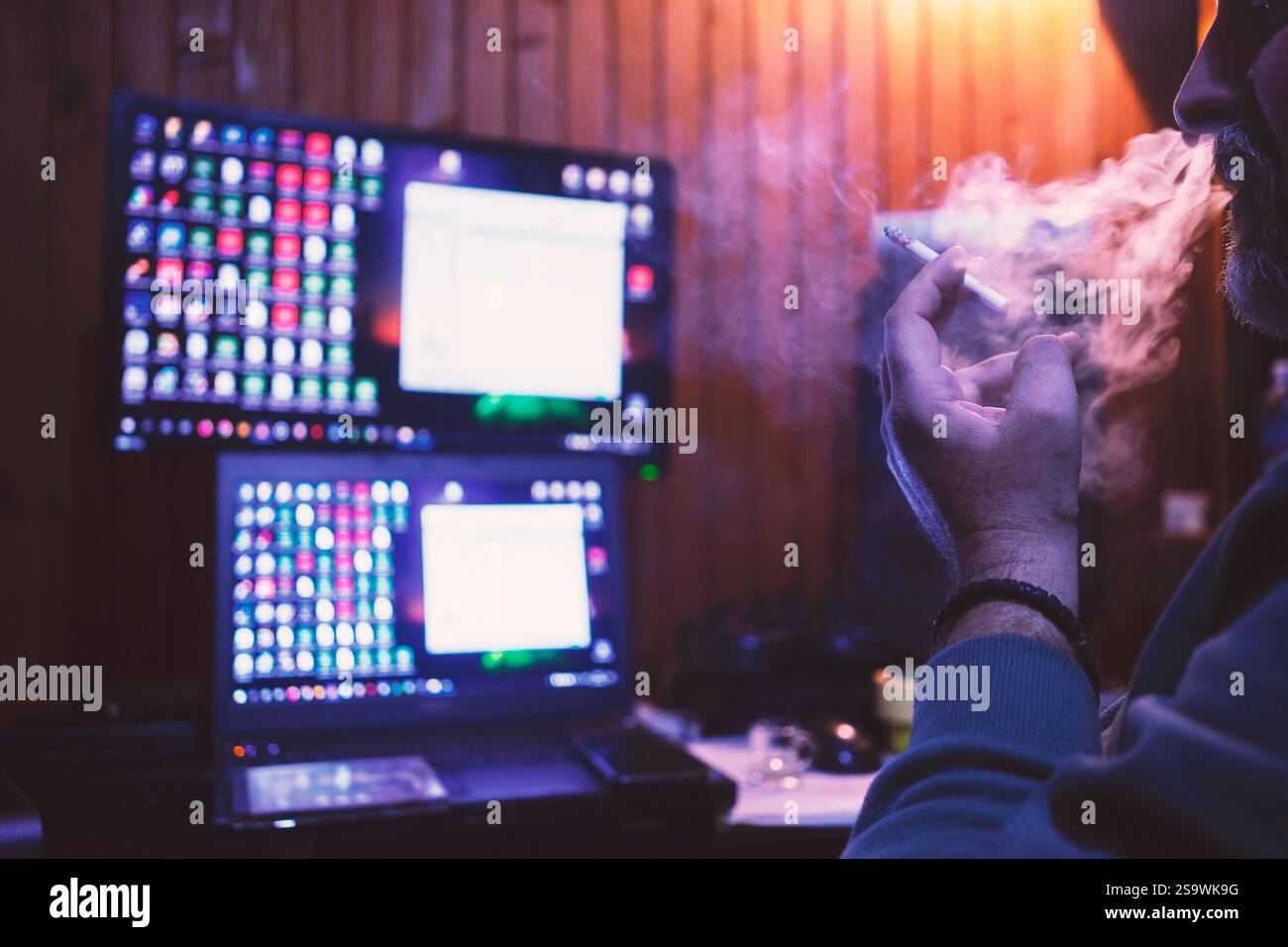 Un homme fume un cigare et regarde son ordinateur, prend une décision sur la prochaine étape. Banque D'Images