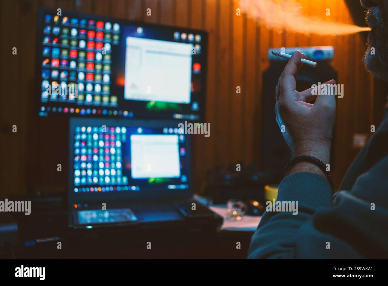 Un homme fume un cigare et regarde son ordinateur, prend une décision sur la prochaine étape. Banque D'Images