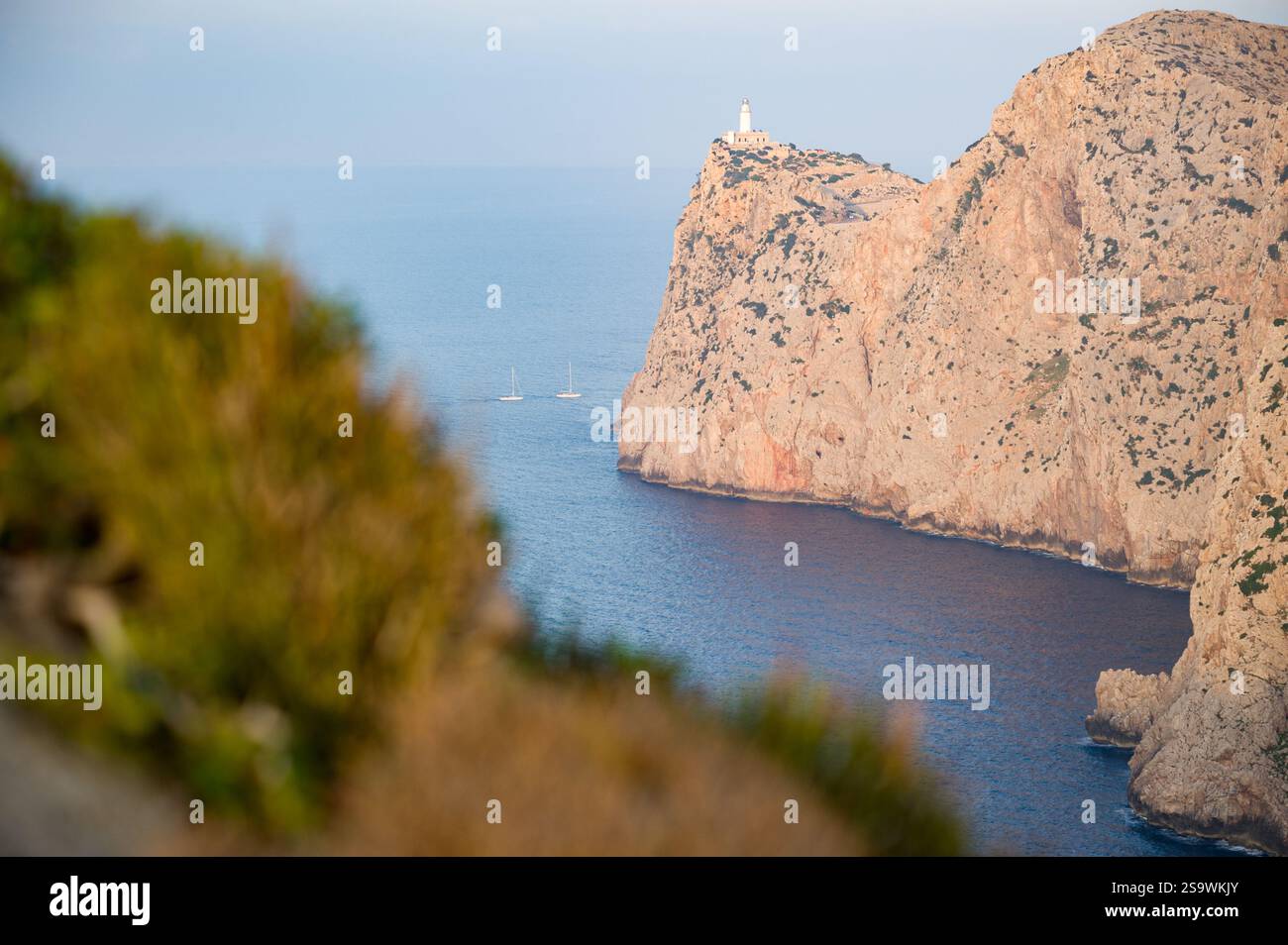 Phare sur une falaise avec voiliers dans la mer, Formentor Espagne Banque D'Images