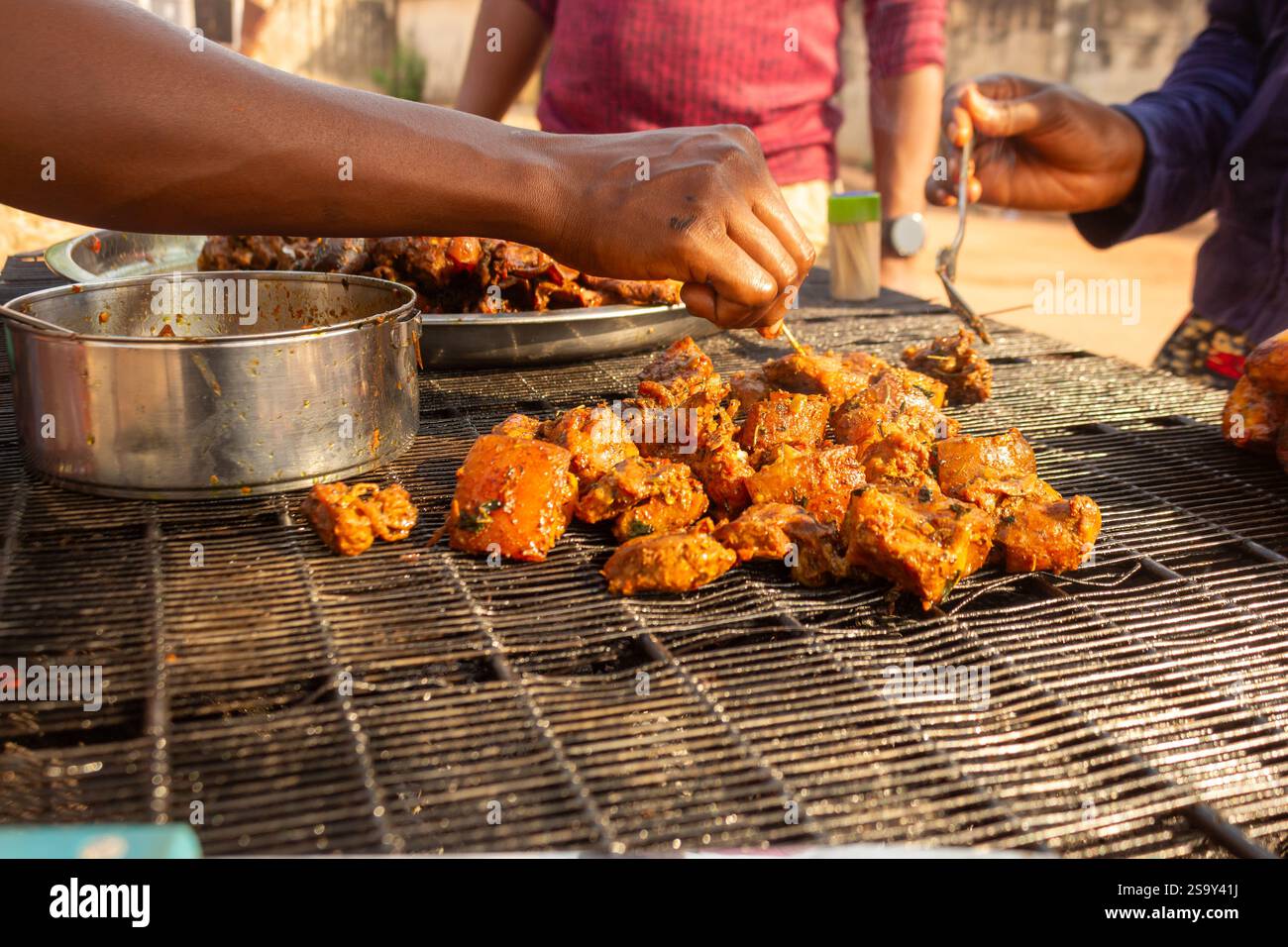 barbecue de street food avec porc et plantains grillant à flamme nue – les mains et le corps du client sont visibles, pas de visages Banque D'Images