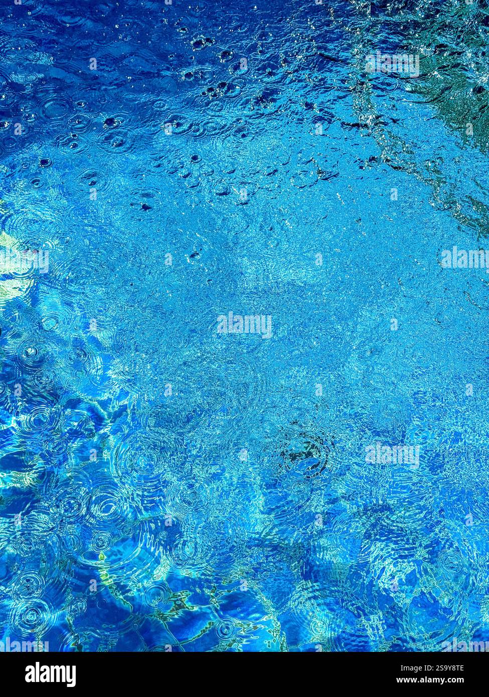 Eau de piscine bleu éclatante avec ondulations gros plan sur le bord d'une piscine présentant une eau bleue éclatante avec ondulations et motifs formés par Wate - Image de stock capturée avec un smartphone