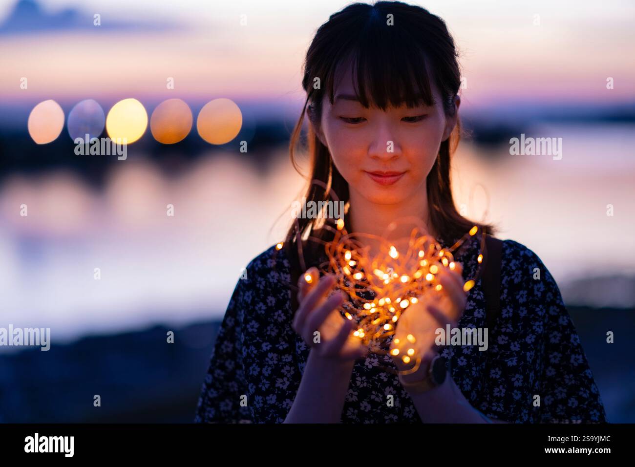 Jeune femme enroulant ses mains autour d'une lumière éclairée Banque D'Images