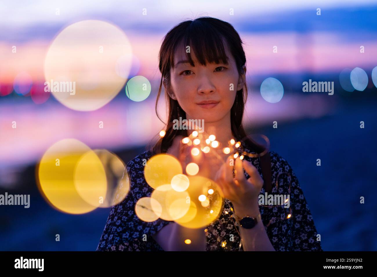 Jeune femme enroulant ses mains autour d'une lumière éclairée Banque D'Images