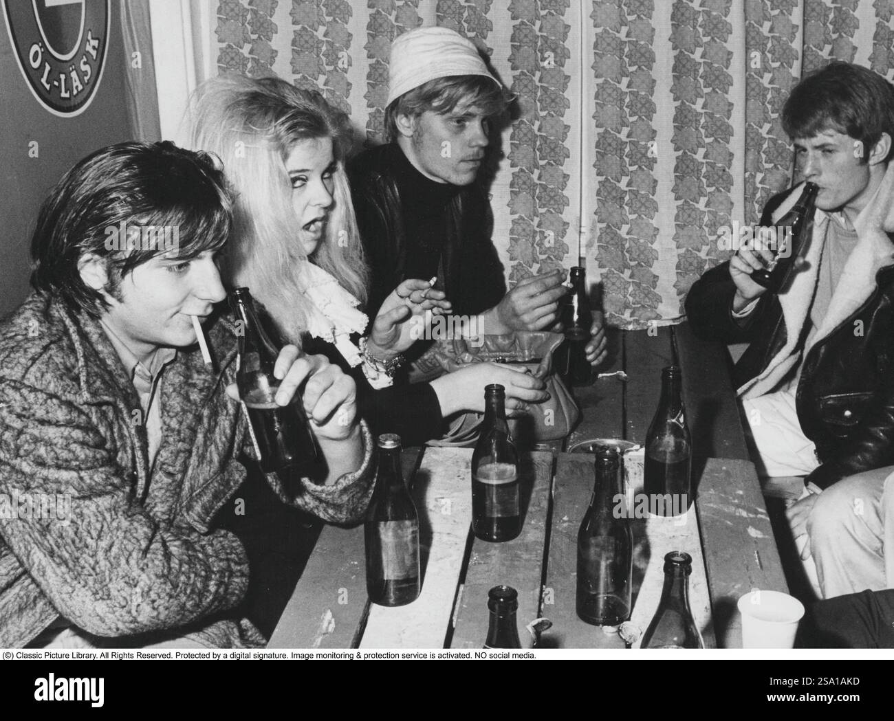 Dans les années 1960 Un groupe de jeunes buvant de la bière et fumant. Pas de verres, juste boire dans les bouteilles de bière. Une image qui illustre des choses très typiques comme la mode et l'apparence des gens dans les années 1960 1968 Banque D'Images