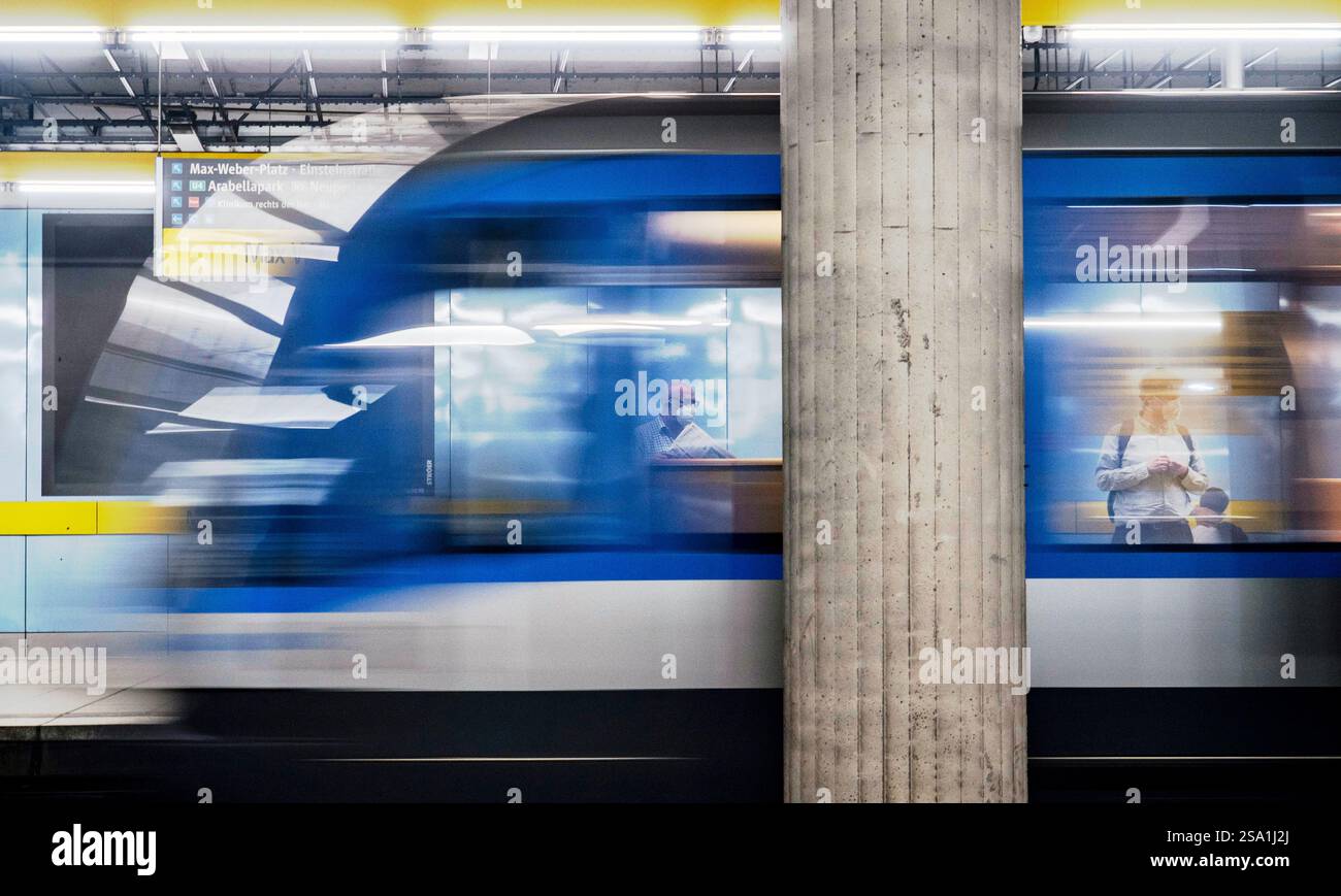 Un plan de mouvement flou d'un train de métro passant devant une plate-forme, avec un pilier en béton en évidence. Les passagers peuvent être vus à l'intérieur du train et sur le pla Banque D'Images