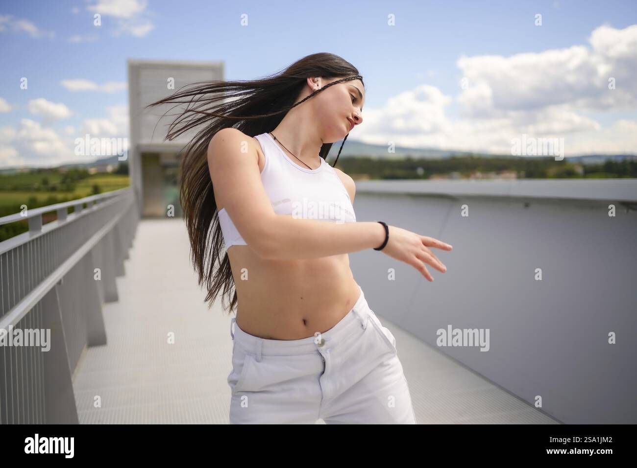 Motion photo d'une jeune femme caucasienne confiante dansant de la musique urbaine sur un pont extérieur Banque D'Images