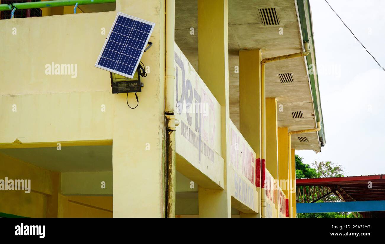 Un panneau solaire installé sur le mur d’une école de village à Iloilo, aux Philippines, assure la lumière pendant les baisses de tension, fournissant un e fiable et durable Banque D'Images