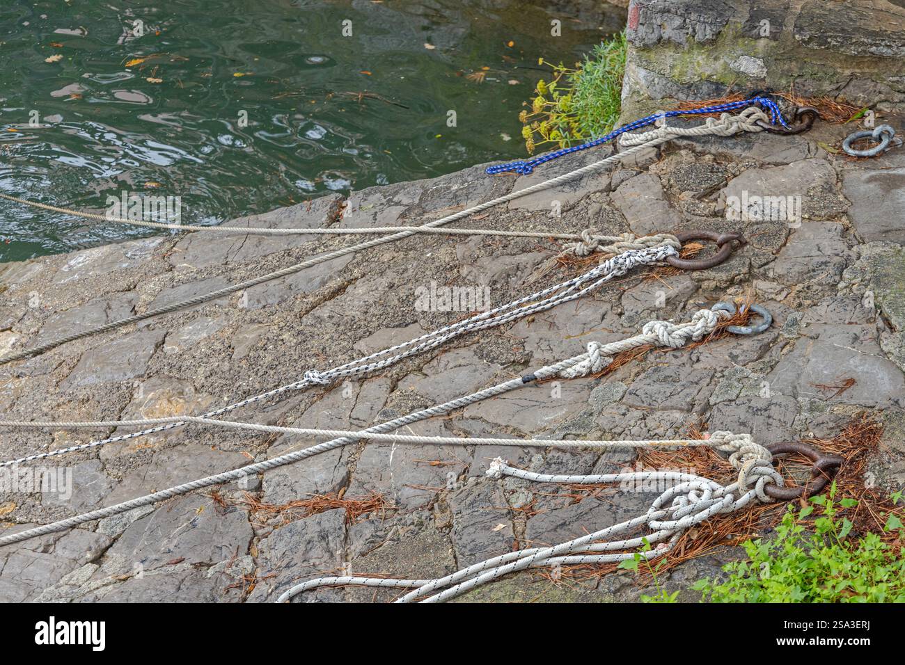 Nœuds de corde de lignes d'amarrage de bateau à Rings à Stone Pier Croatie Banque D'Images