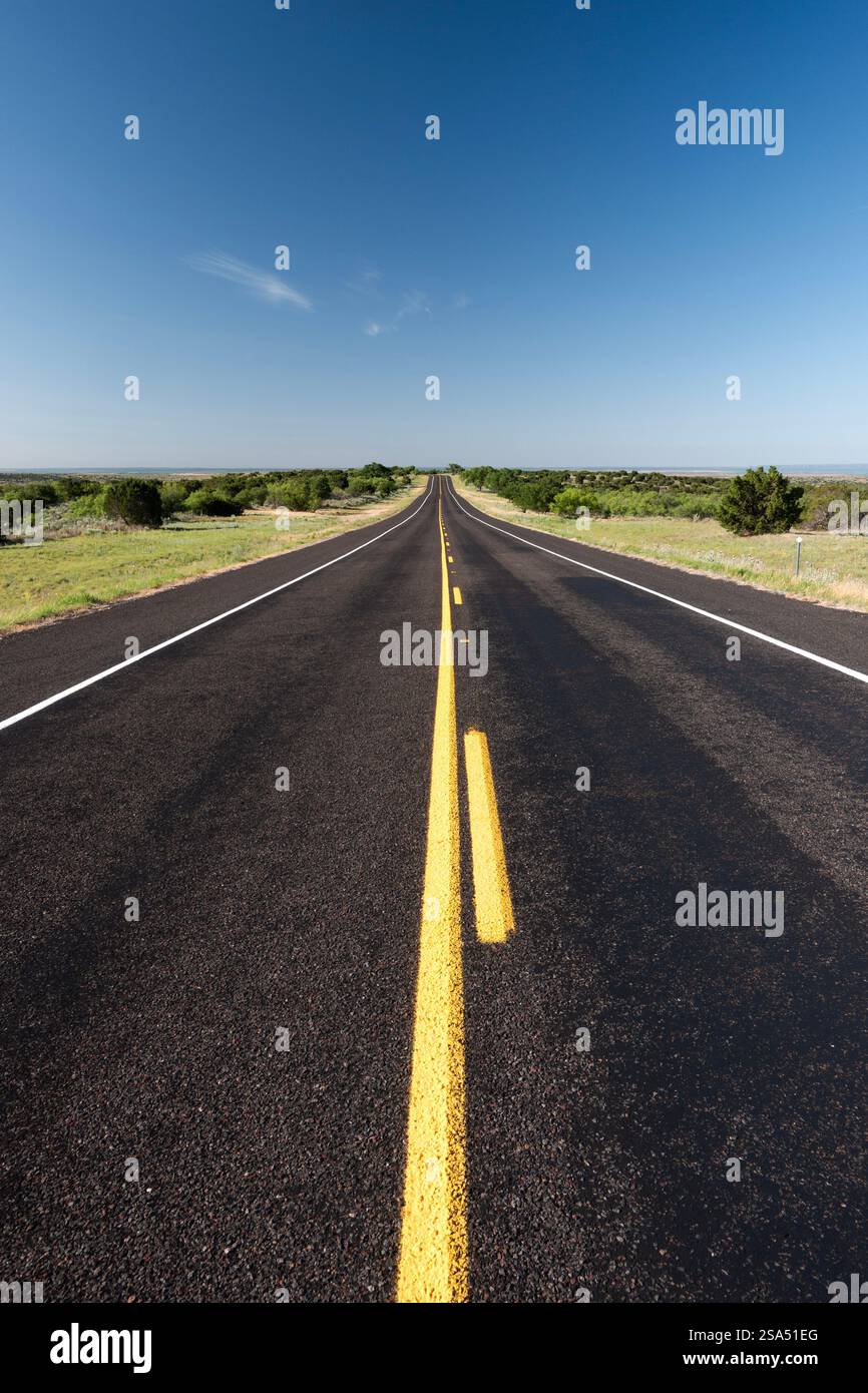 Vue verticale regardant directement le long d'une route asphaltée avec des lignes convergentes vers l'horizon dans le Texas Panhandle Banque D'Images