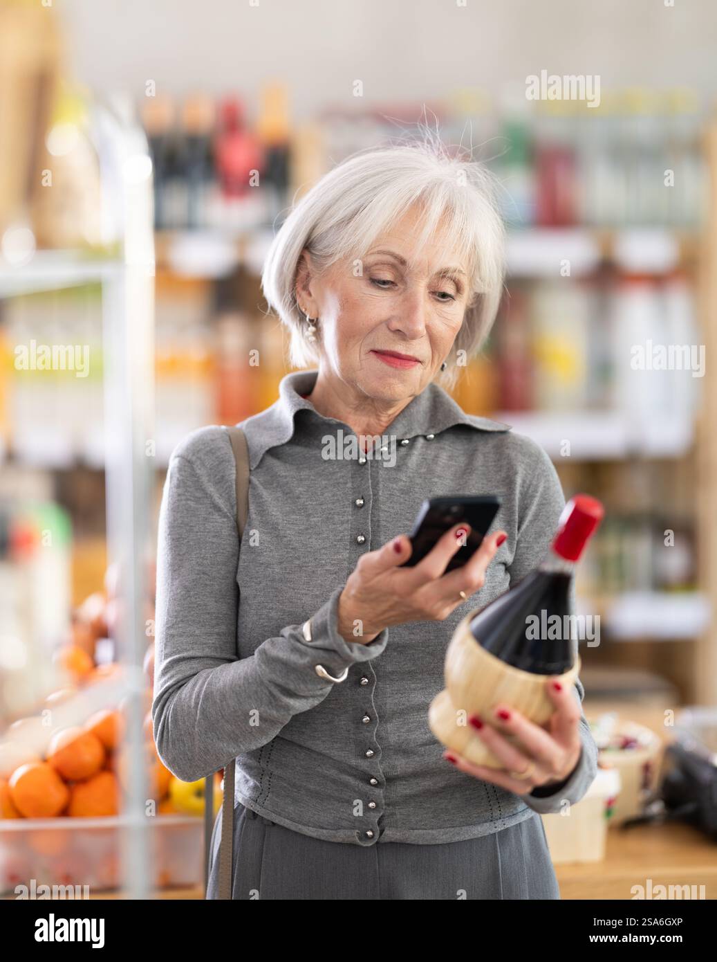 Femme âgée scannant le code qr du vin Banque D'Images