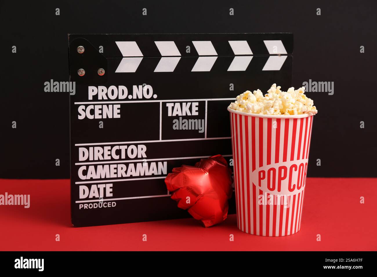 Seau de pop-corn avec batteur de film et ballon à air en forme de coeur sur fond coloré. Célébration de la Saint-Valentin Banque D'Images