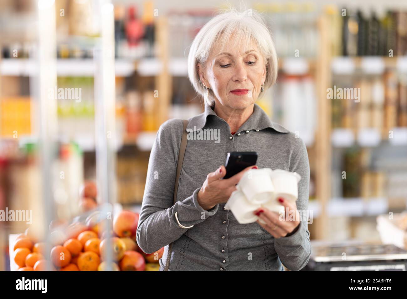 Femme âgée scannant le code qr pour le yaourt Banque D'Images
