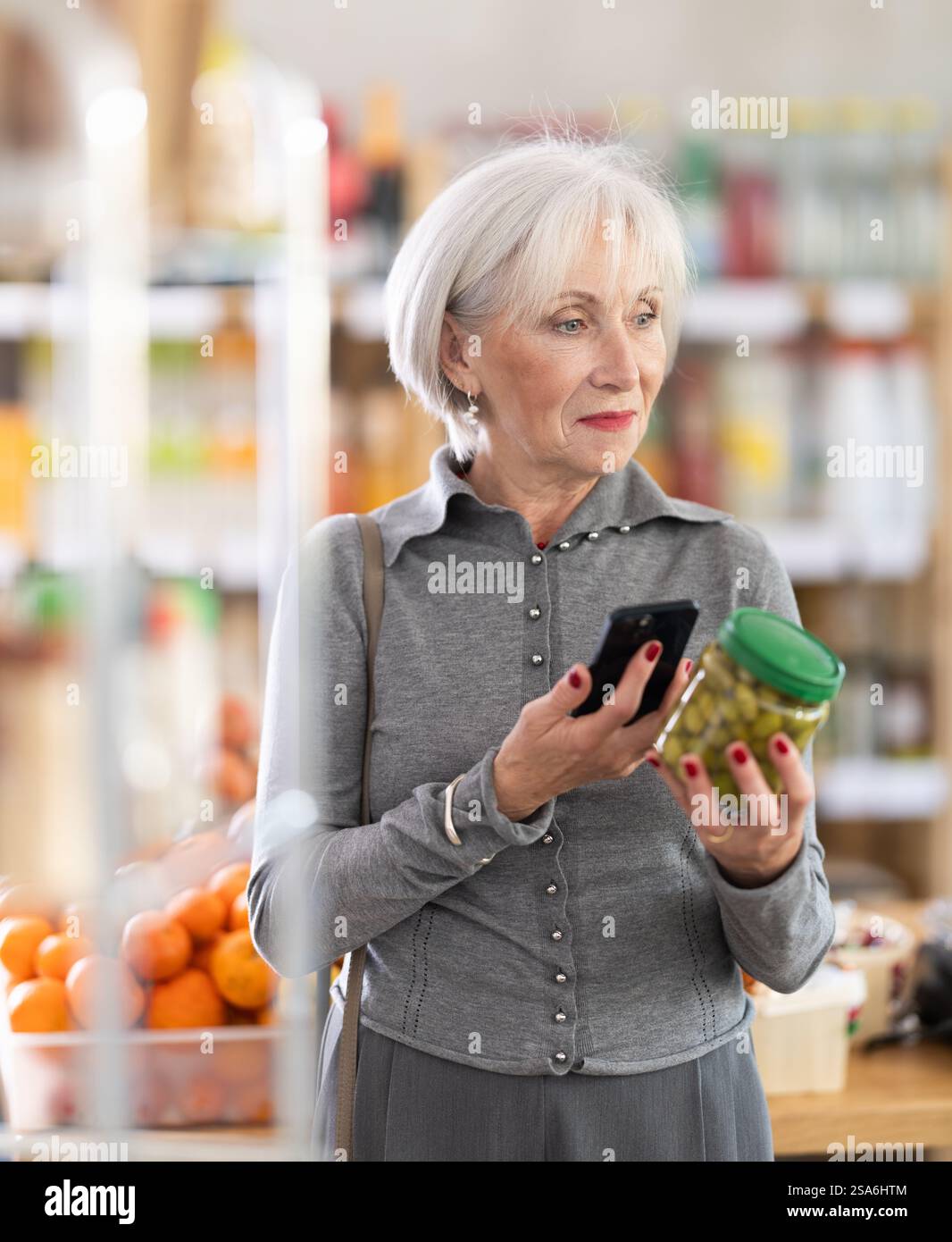 Femme âgée scannant le code qr pour les olives Banque D'Images