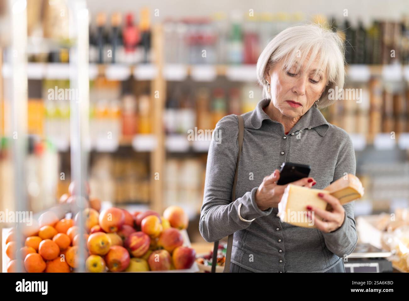 Femme âgée scannant le code qr pour le fromage Banque D'Images