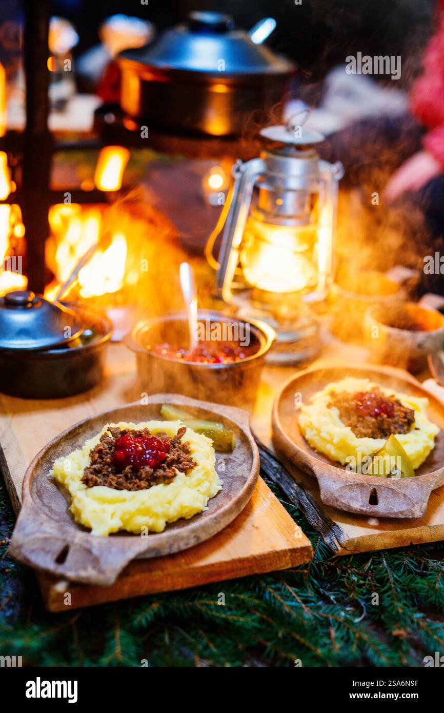 Rennes sautés avec purée de pommes de terre et airelles servis dans une cabane lappish à côté d'un feu ouvert Banque D'Images