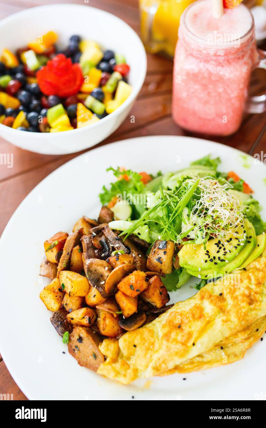 Petit-déjeuner végétarien avec omelette, pommes de terre rôties, saucisses à base de plantes, champignons sautés et avocat Banque D'Images