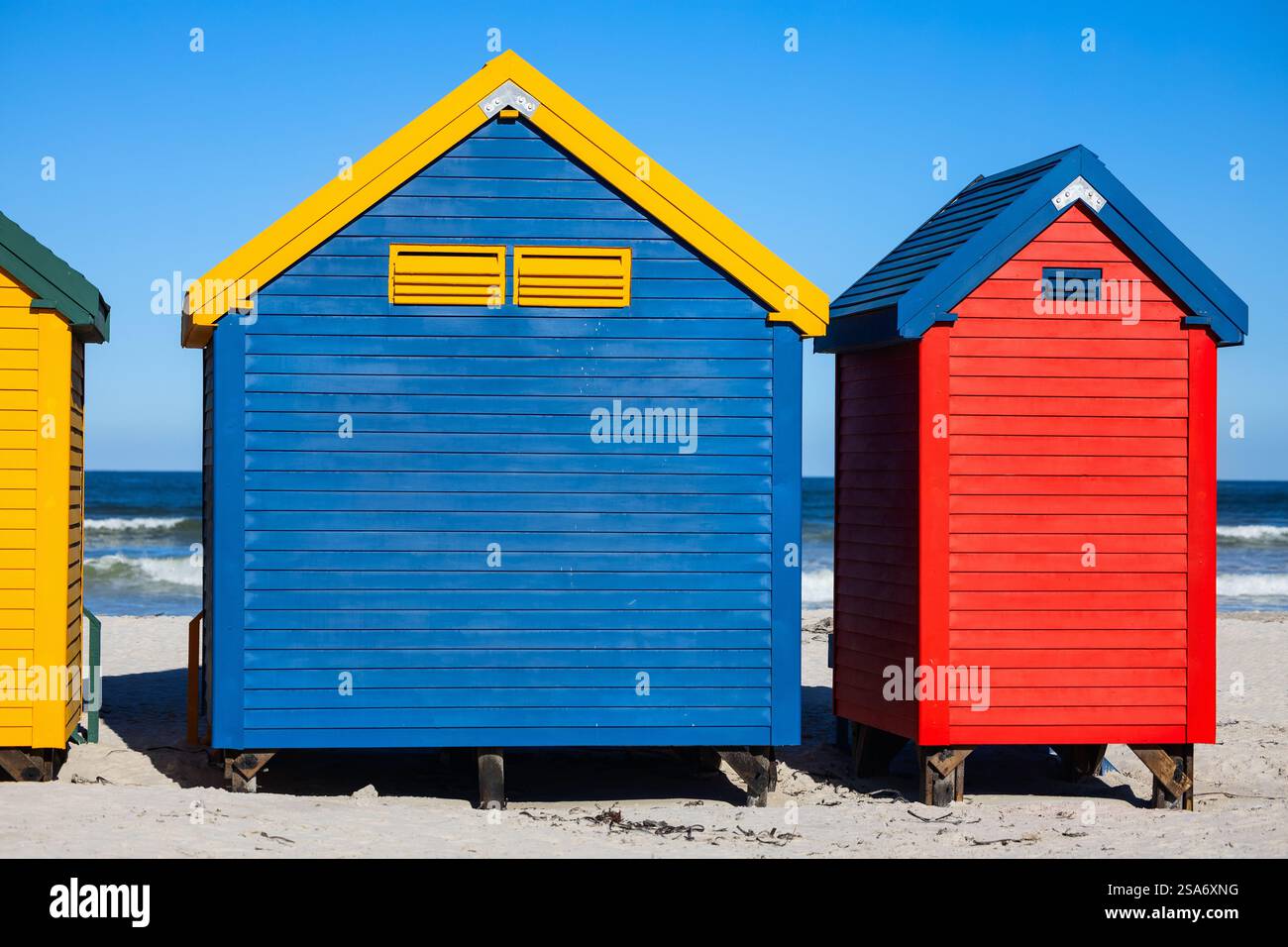 Rangée de boîtes à langer de style victorien bleu, jaune, rouge et vert distinctif sur pilotis le long du célèbre littoral sablonneux de Muizenberg Banque D'Images