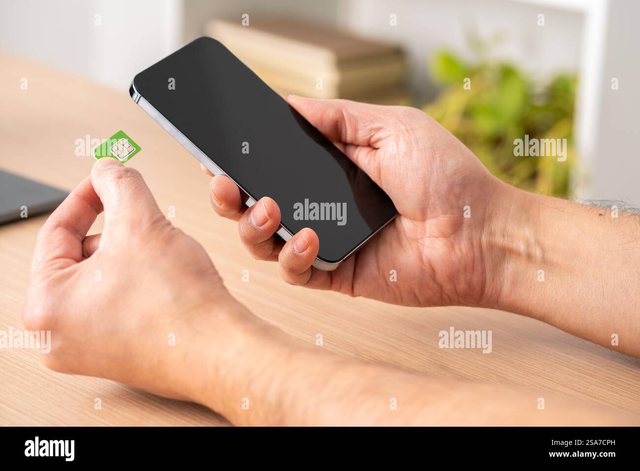 Gros plan des mains d'un homme mettant la carte sim sur le téléphone sur une table Banque D'Images