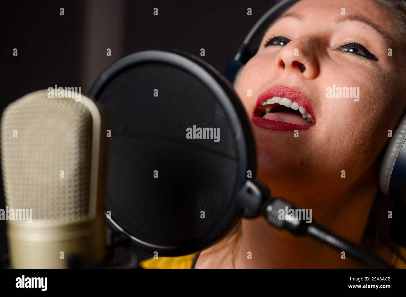 Jeune chanteuse portant des écouteurs enregistrant une nouvelle chanson dans un studio professionnel Banque D'Images
