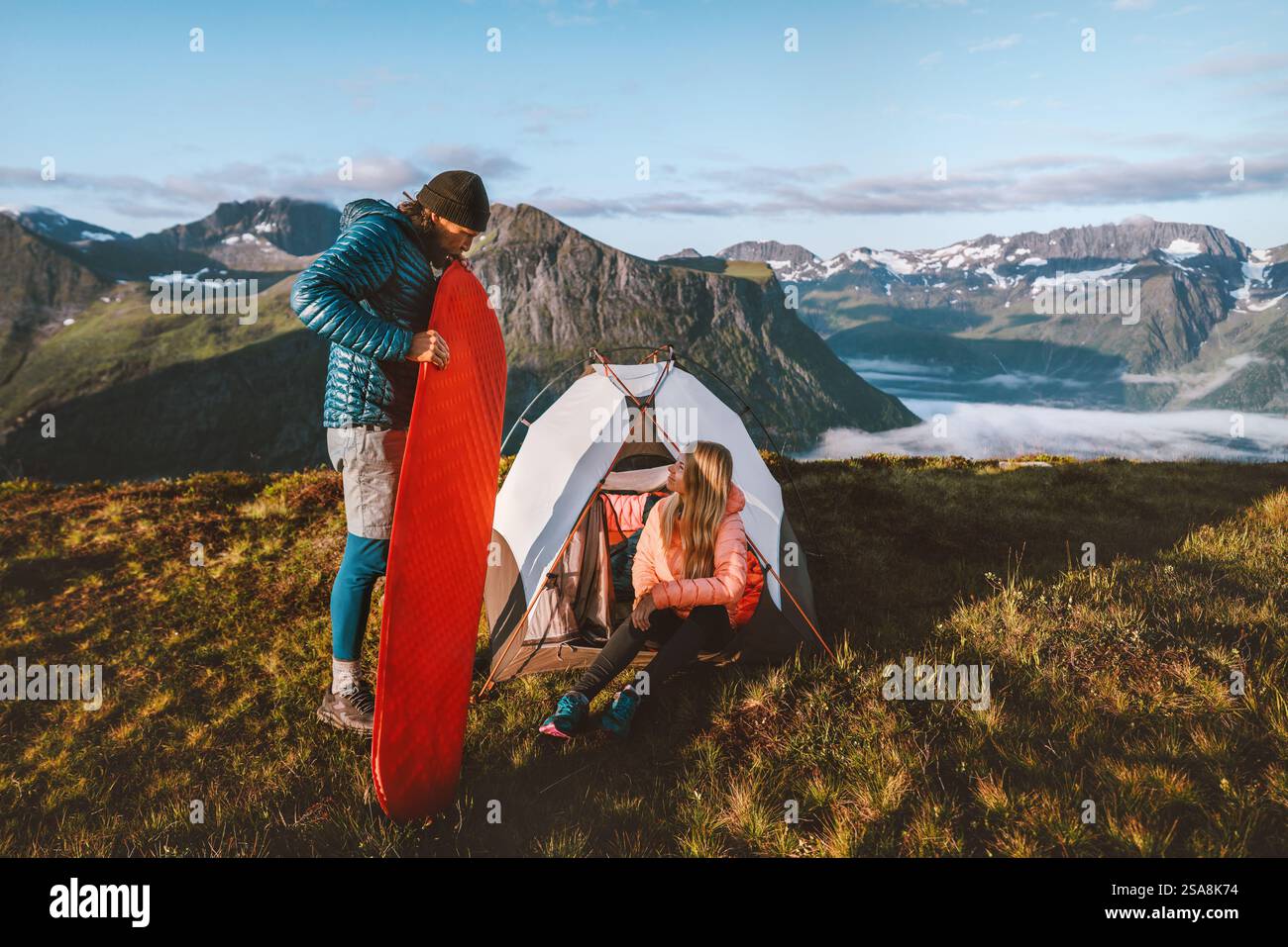 Amis de couple installant le voyage de matériel de camping de tente dans les montagnes, homme gonflant matelas de couchage, vacances actives aventures en plein air homme et femme randonnée Banque D'Images