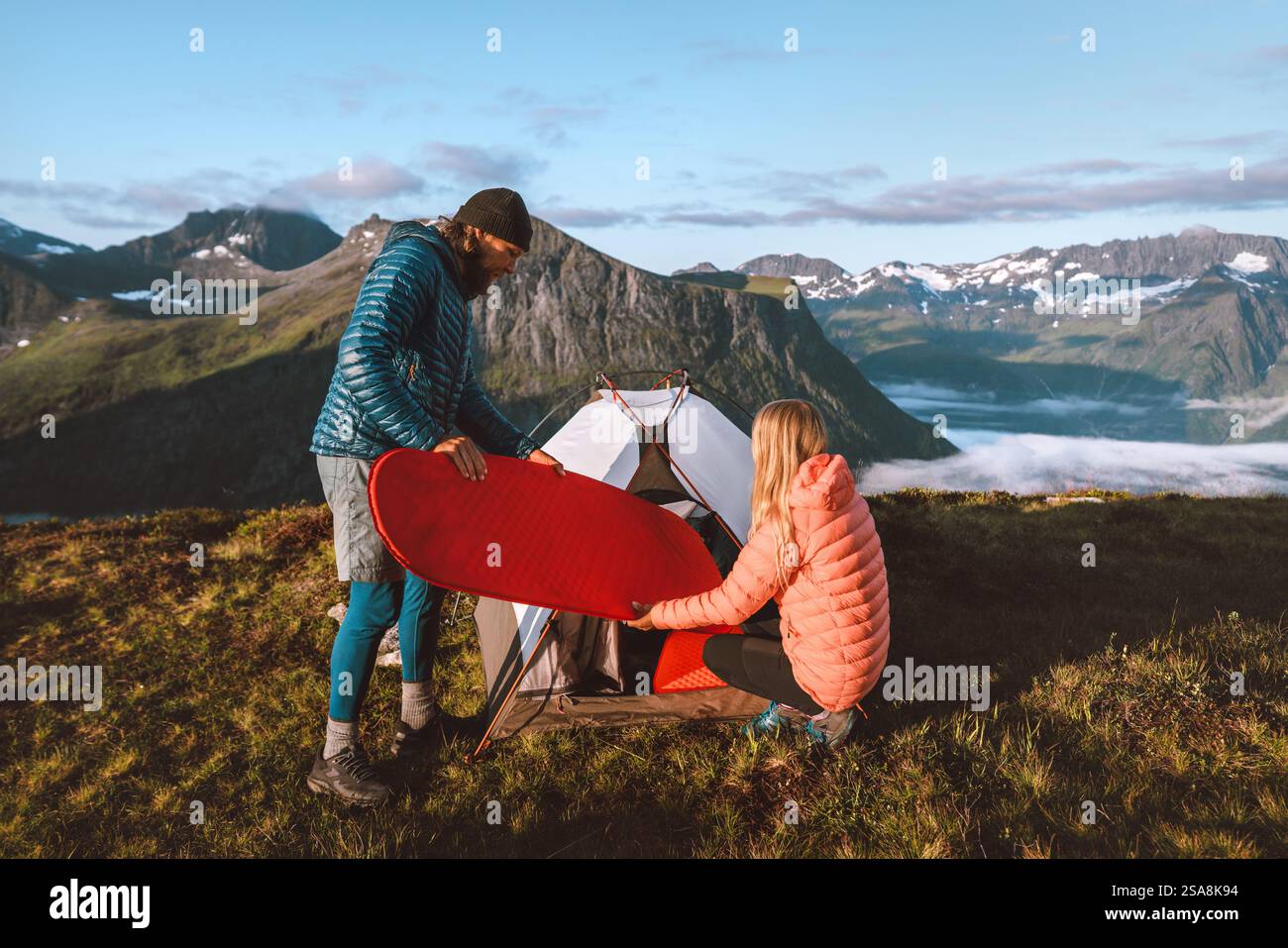 Les amis de couple mettent un matelas de couchage dans le matériel de camping de tente dans les montagnes, les vacances actives voyagent en plein air, l'homme et la femme faisant de la randonnée ensemble des aventures familiales à Banque D'Images