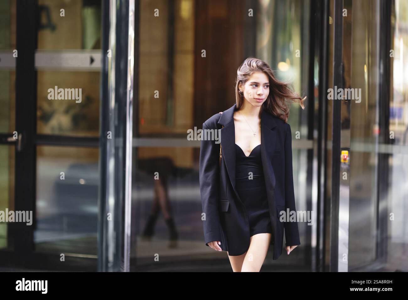 Jeune femme à la mode portant une tenue élégante oversize blazer noir, beau modèle avec cheveux foncés marchant ville urbaine. Mode moderne, Street style Banque D'Images