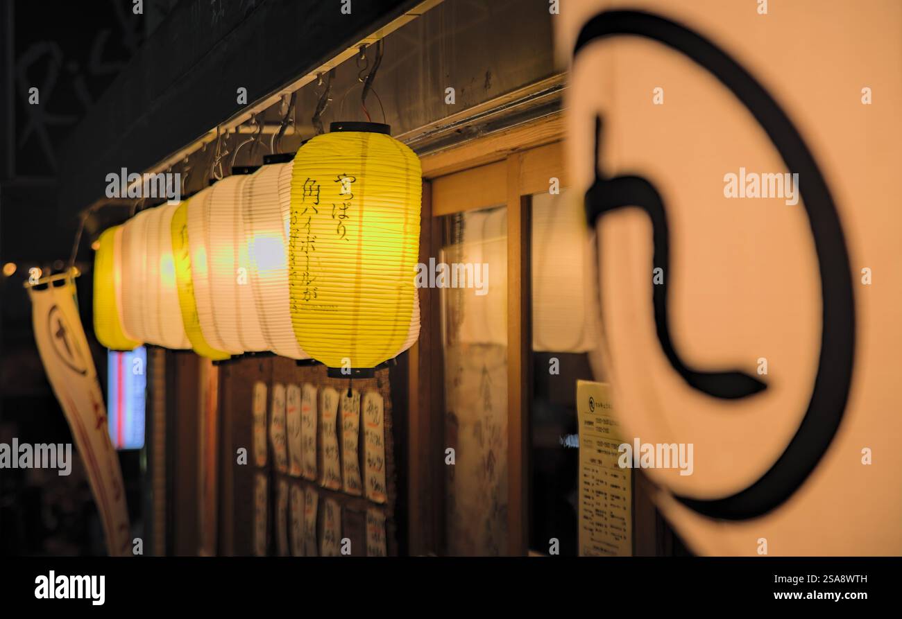 Vue nocturne sur une rangée de lanternes en papier éclairées suspendues devant un restaurant dans l'ouest de Tokyo Banque D'Images