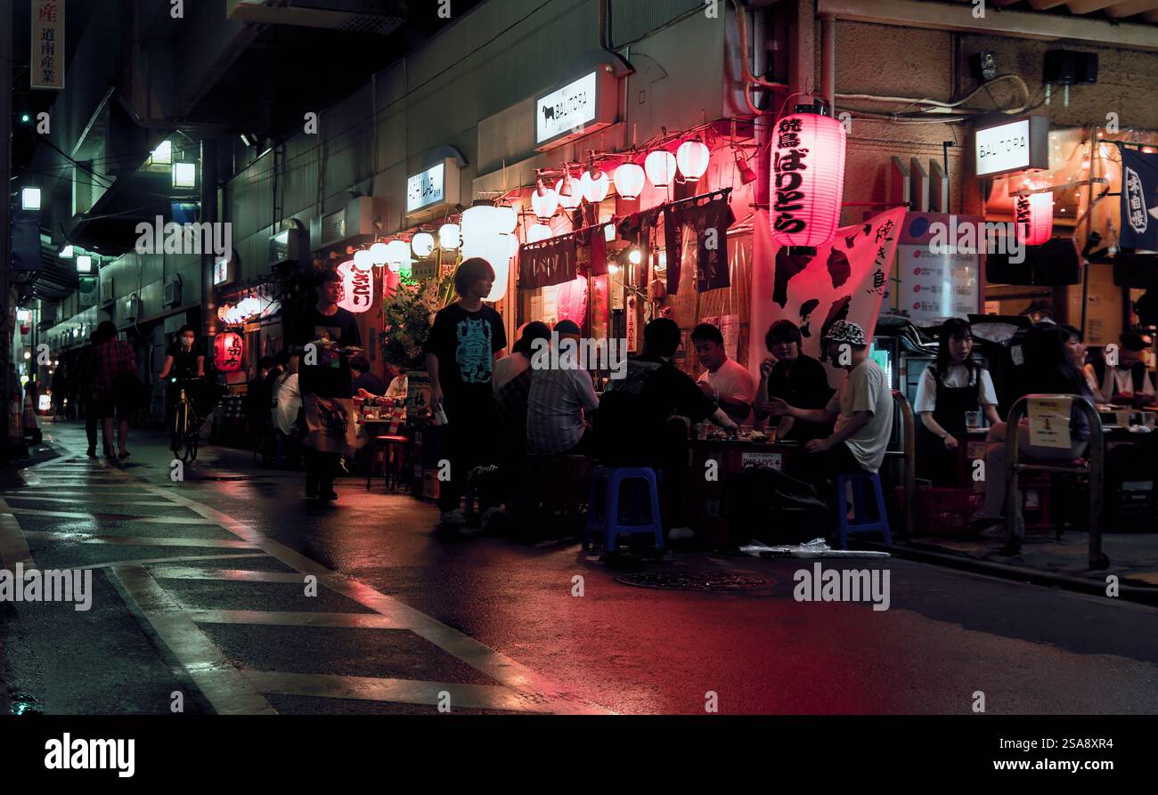 Vue nocturne colorée d'un certain nombre de clients mangeant et buvant dans un bar-restaurant situé sous les voies ferrées surélevées dans l'ouest de Tokyo Banque D'Images